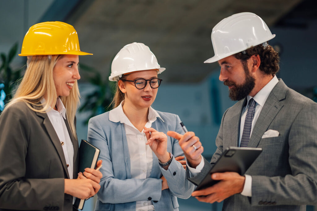Construction business owner meeting with a project manager or team while reviewing plans.