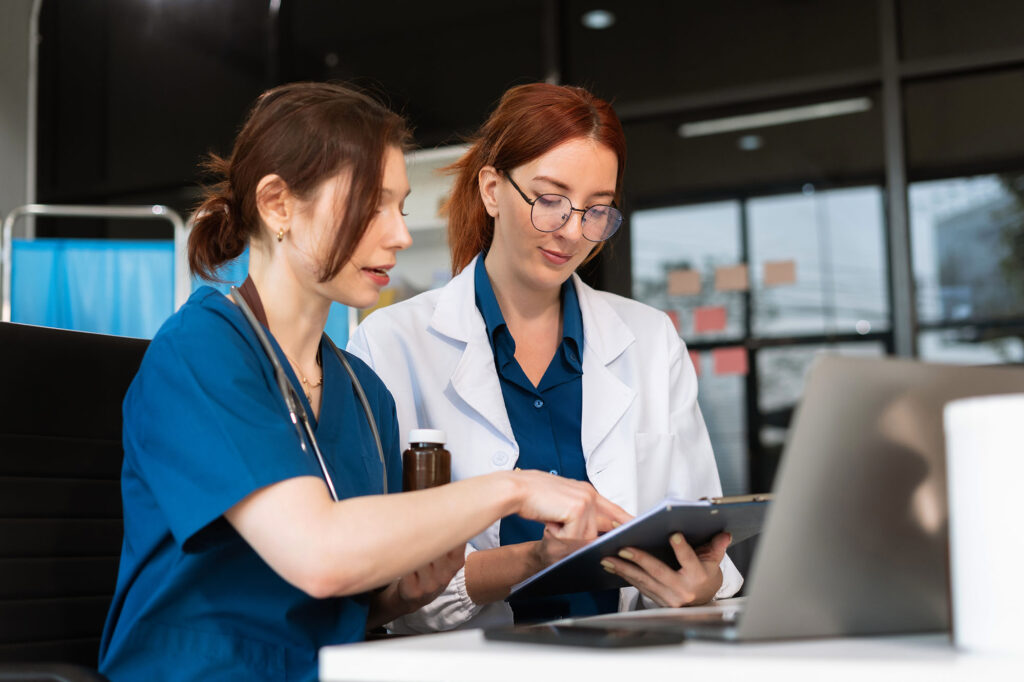 Medical practice owner and team member reviewing financial or operational information on a laptop.